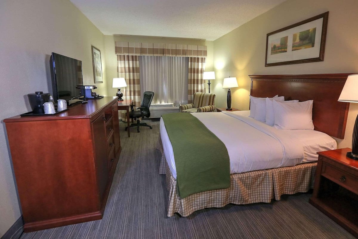 Une chambre d’hôtel équipée d’un lit, d’un bureau, d’une chaise, de lampes et d’un téléviseur.