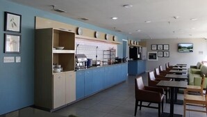 A restaurant with a long counter, blue walls, and multiple seating areas.