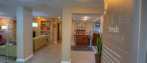 A hotel lobby with a reception desk, a welcome mat, and a wall with an update notice.