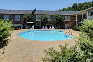 A swimming pool with lounge chairs and a building in the background. - Country Inn & Suites by Radisson, Charlotte I-85 Airport, NC (Charlotte)
