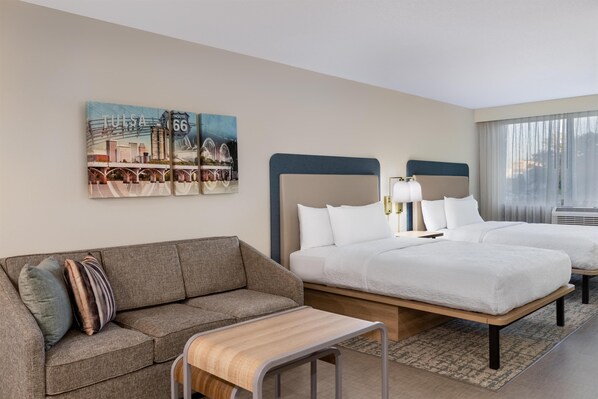 A hotel room with a bed, a sofa, a small table, and a painting of a cityscape.