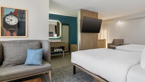 A hotel room with a bed, a sofa, a TV, a mirror, and a clock on the wall. - Homewood Suites by Hilton Tulsa South Medical District (Tulsa)