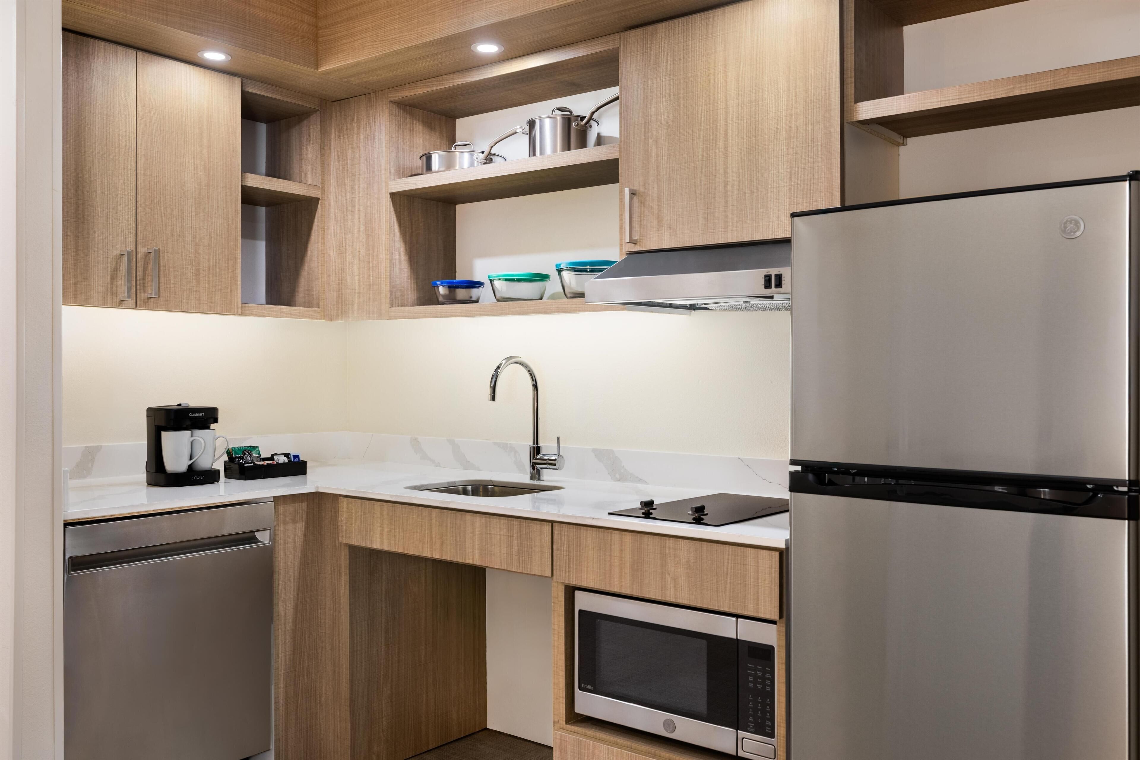 Una cucina moderna con mobili in legno, elettrodomestici in acciaio inossidabile, forno integrato e macchina da caffè.