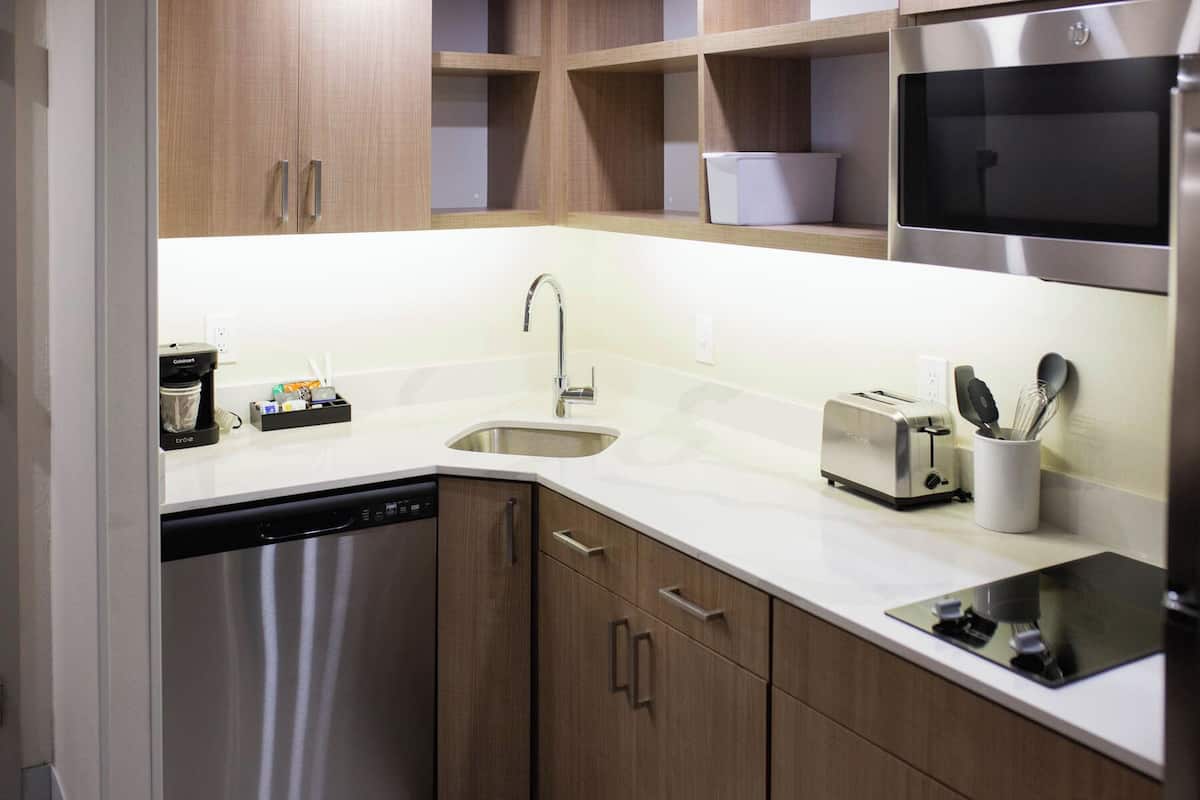 A modern kitchen with stainless steel appliances, wooden cabinets, and a white countertop.