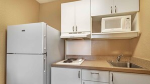 A compact kitchenette with a white refrigerator, a microwave, a stove, and a sink. - Extended Stay America Suites Cincinnati Springdale I275 (Cincinnati)