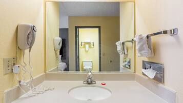 A bathroom with a sink, mirror, towel rack, and hand dryer.