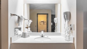 Une salle de bain avec un lavabo blanc, un miroir, un porte-serviettes et un sèche-cheveux.