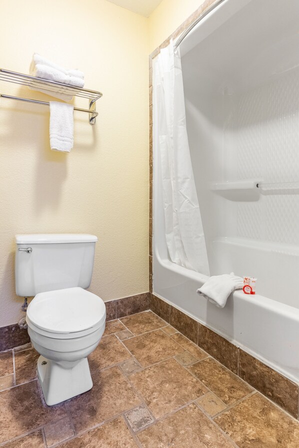 Une salle de bain comprenant des toilettes, une douche avec un rideau et un porte-serviettes avec des serviettes.