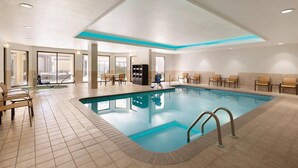 Ein Innenpool mit Fliesenboden, blauer Poolkante und Deckenleuchten.