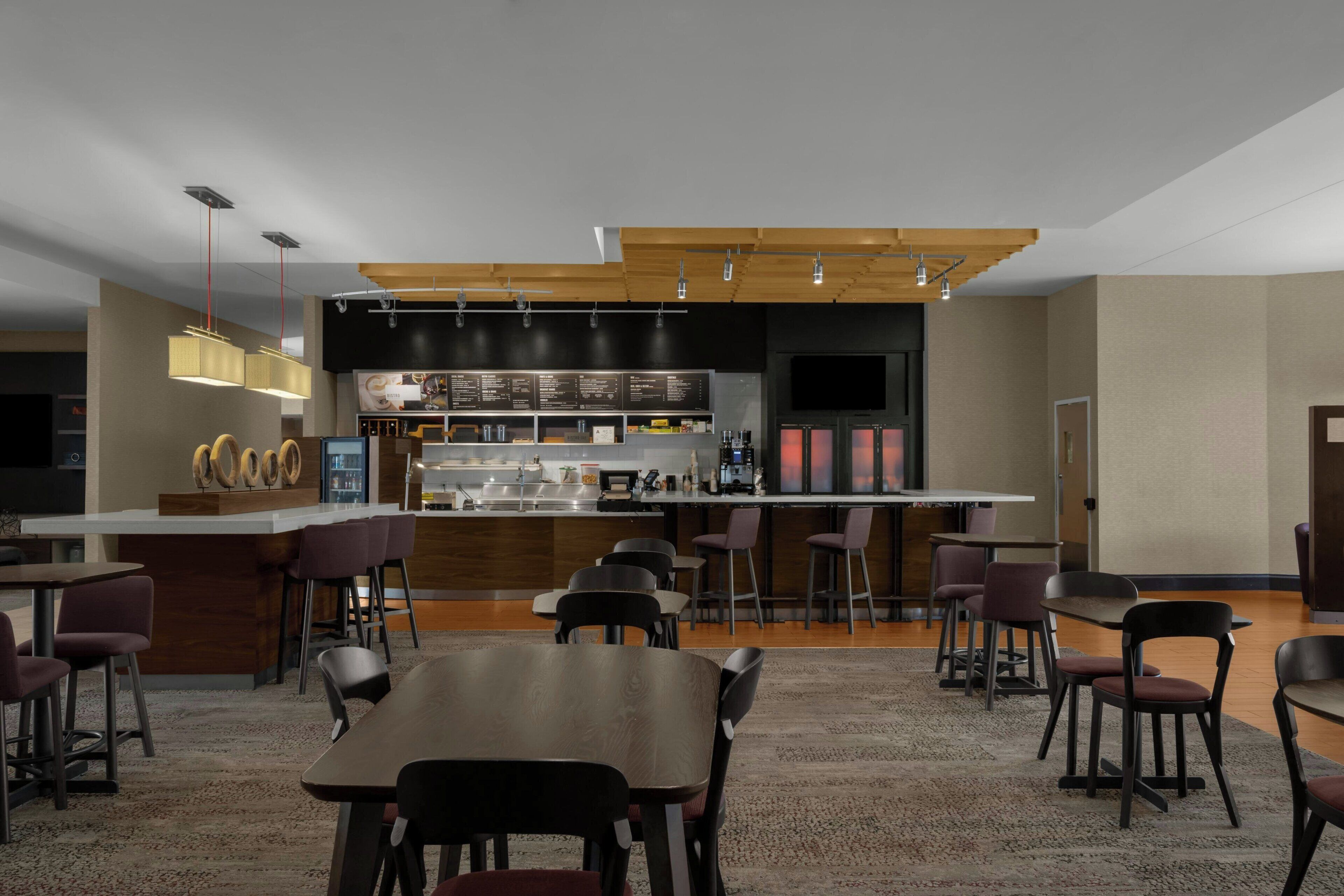 Un moderno vestíbulo de hotel con zona de bar, asientos y mostrador de recepción.