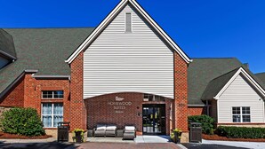 A hotel with a brick facade, a large entrance, and a sign that reads "Homewood Suites Hilton".