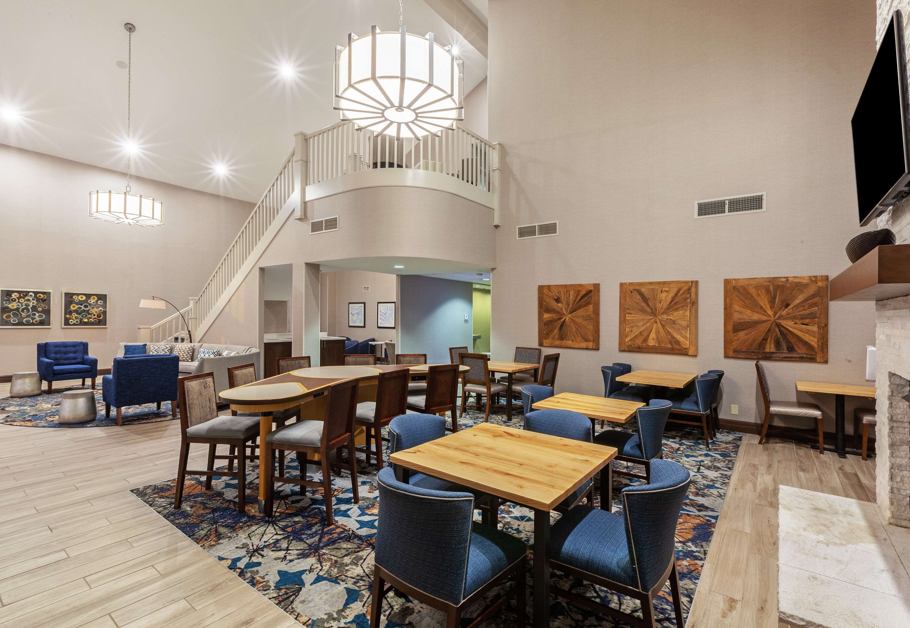 Un'ampia hall d'albergo con una scalinata centrale, diverse zone salotto e un grande lampadario.