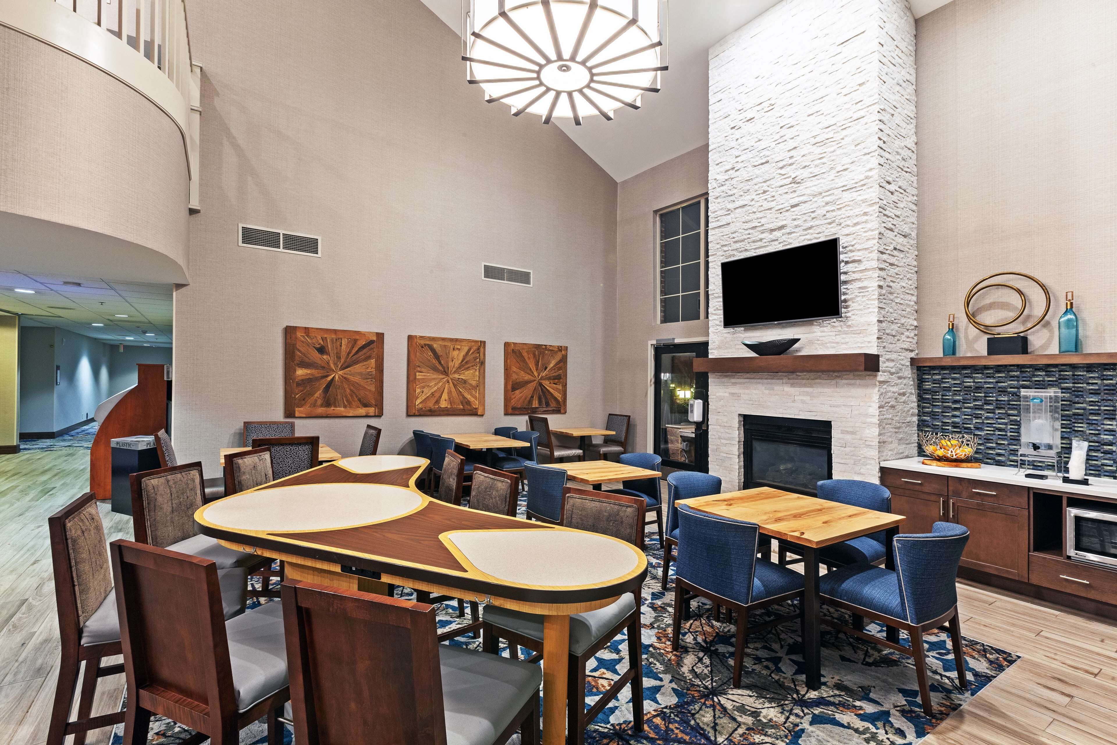 Un espace repas moderne avec des tables et des chaises en bois, une cheminée et un téléviseur à écran plat fixé au mur.