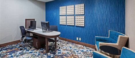 A conference room with a blue textured wall, a patterned carpet, and modern furniture including a desk, chairs, and a sofa.