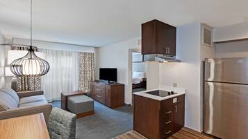 Una habitación de hotel moderna con kitchenette, un sofá, un televisor y un comedor.