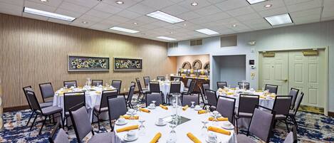 A conference room with round tables, chairs, and a carpeted floor.