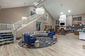Relax in a spacious living area with a curved sofa and armchairs, surrounded by a chandelier and a patterned rug.