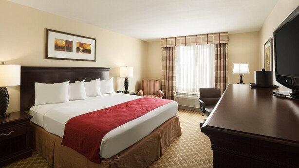 A hotel room with a large bed, a desk, a chair, a television, and a window with curtains. - Country Inn & Suites by Radisson, Tulsa, OK (Tulsa)