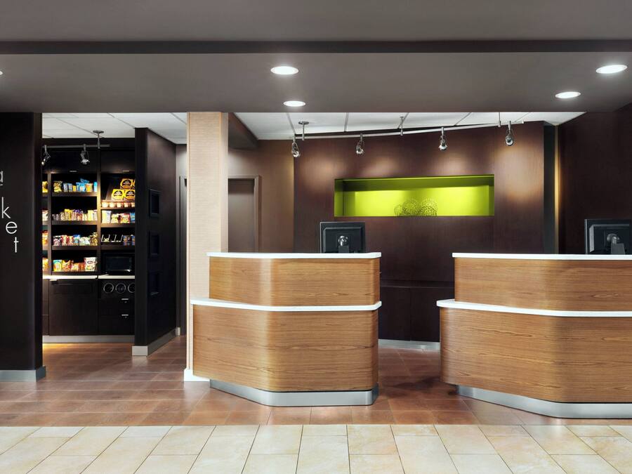 A reception area with a wooden reception desk, a green illuminated wall, and a shelf with snacks.