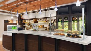 Zona de bar moderna con mostrador curvo, lámparas colgantes y un tablero de menú.