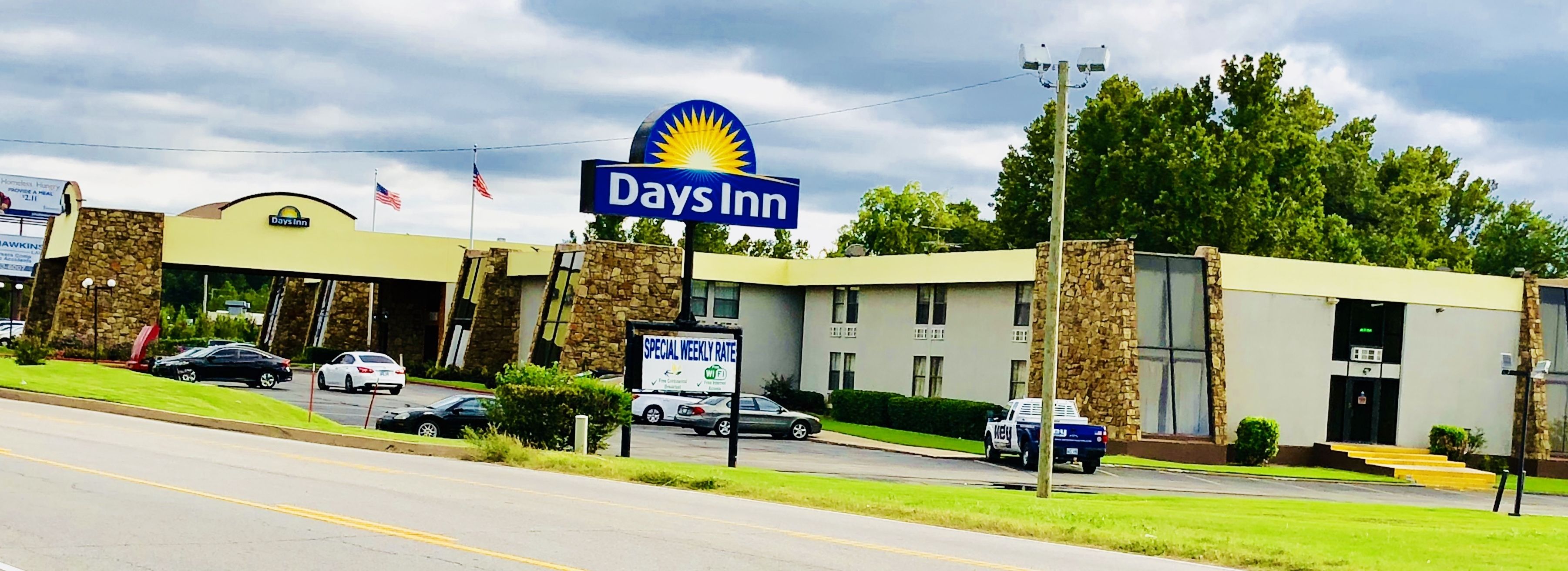 A Days Inn with a stone facade, multiple parking spaces, and a clear sky.