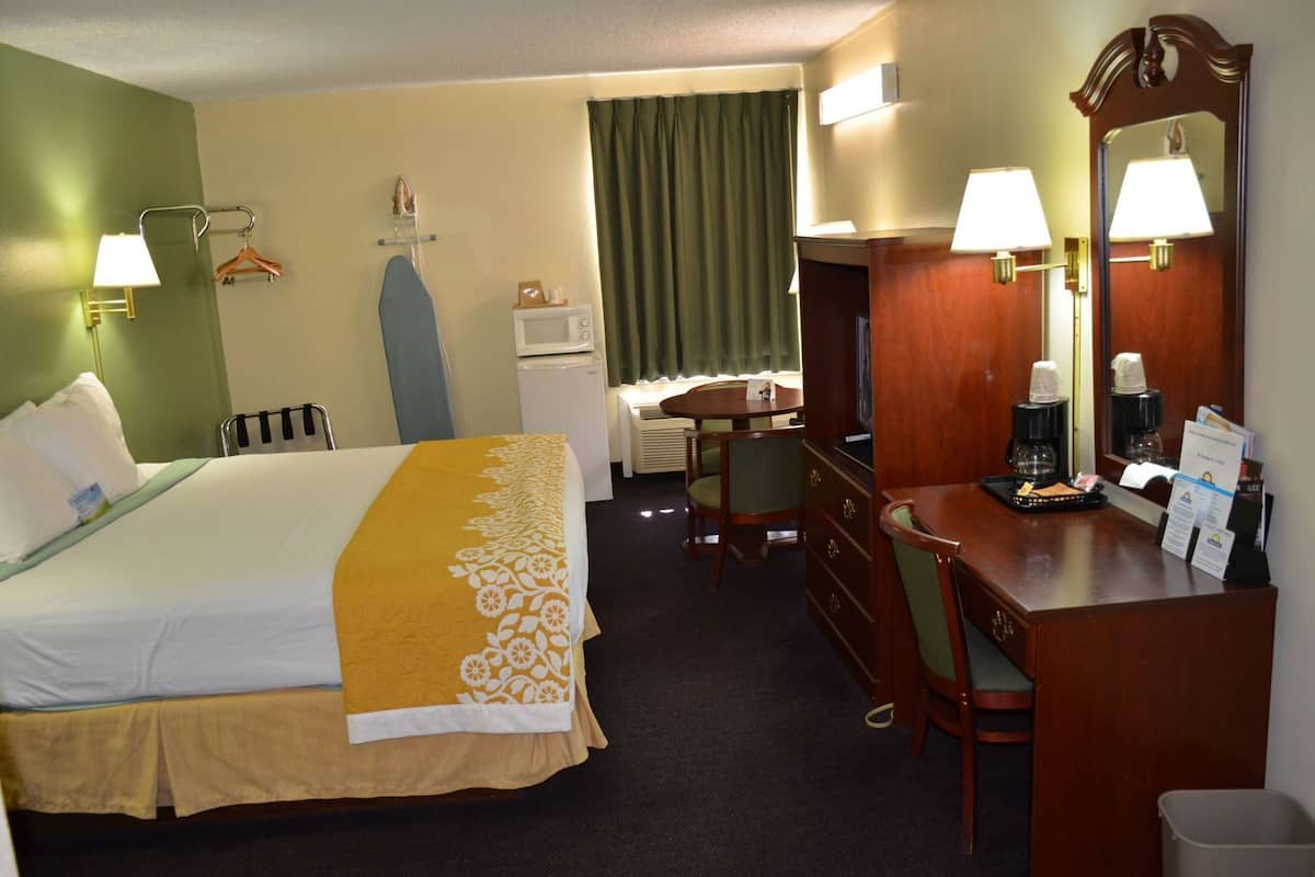 Une chambre d’hôtel avec un lit, un bureau, une chaise et un miroir.