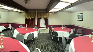 A conference room with multiple tables and chairs, a podium, and framed pictures on the walls.