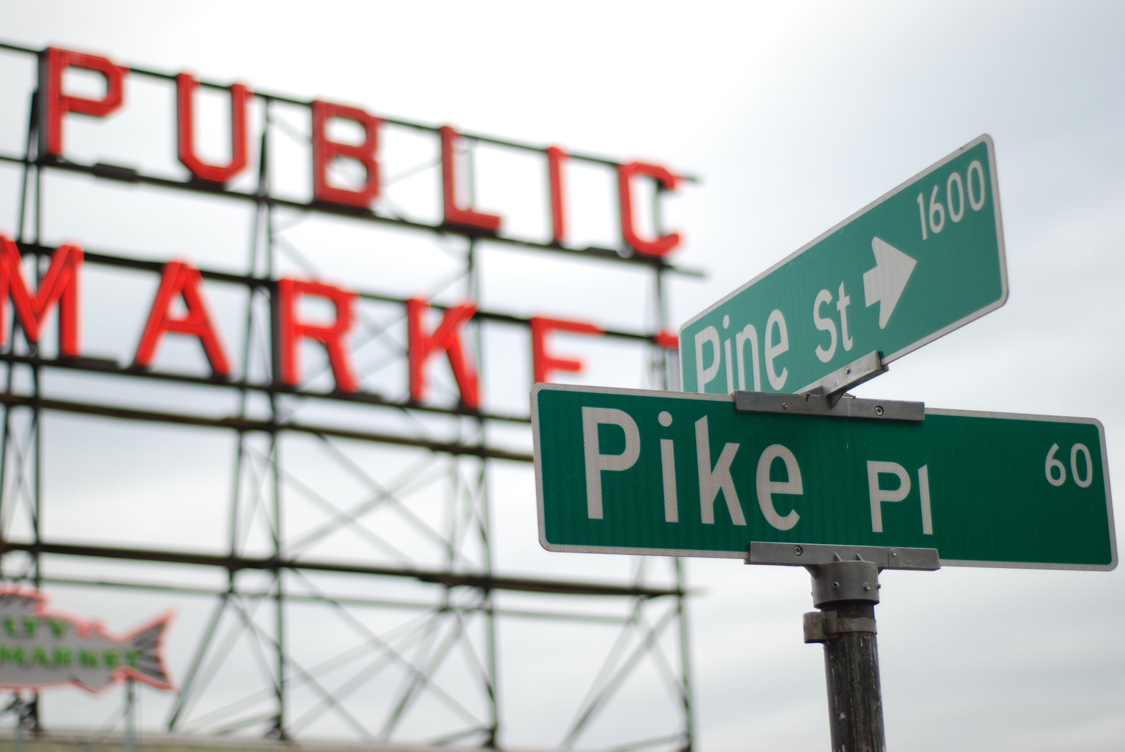 Señales de calle que indican Pine St y Pike Pl, con un cartel grande al fondo que dice 'PUBLIC MARKET'.