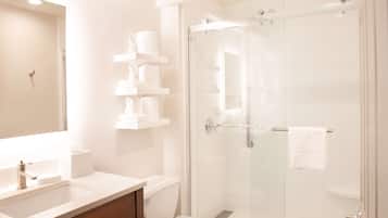 Un baño moderno con ducha de vidrio, lavabo blanco y inodoro.