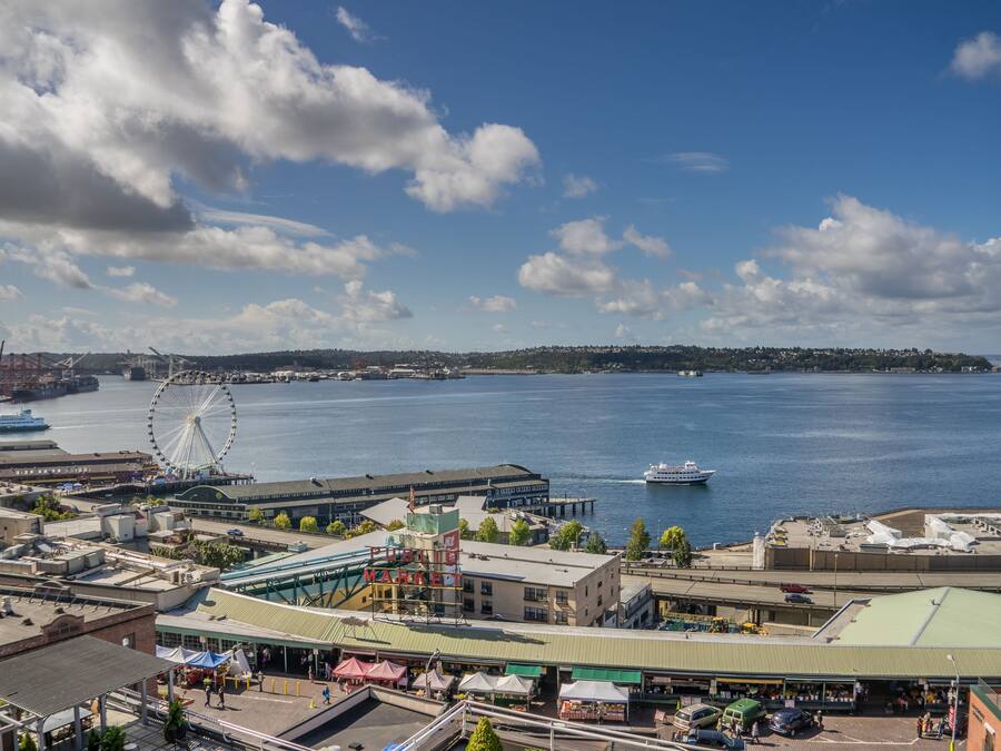 Une vue urbaine sur le front de mer, avec une grande roue bien visible, un navire de croisière et un ferry amarré.