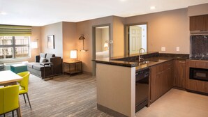 A modern kitchen with a dishwasher, wooden cabinets, and a granite countertop. - Hampton Inn & Suites Seattle-Downtown (Seattle)