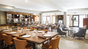 A spacious dining area with multiple tables and chairs, a kitchen in the background, and large windows allowing natural light. - Four Points by Sheraton Downtown Seattle Center (Seattle)