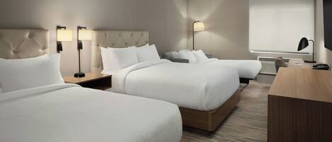 A hotel room with two beds, a desk, a chair, a TV, and a window with blinds.