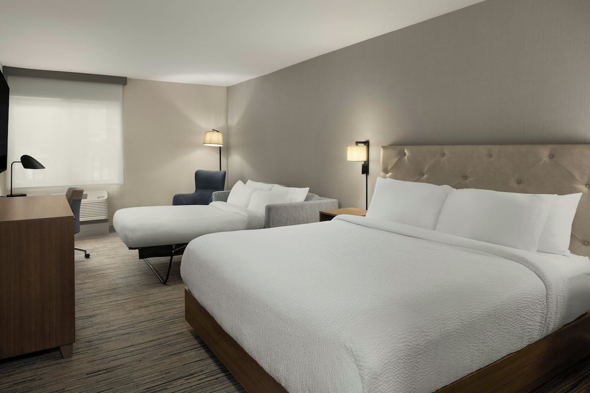 Una habitación de hotel con una cama grande, un escritorio, una silla y dos lámparas de noche.