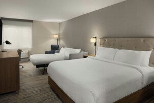 Una habitación de hotel con una cama grande, un escritorio, una silla y dos lámparas de noche.