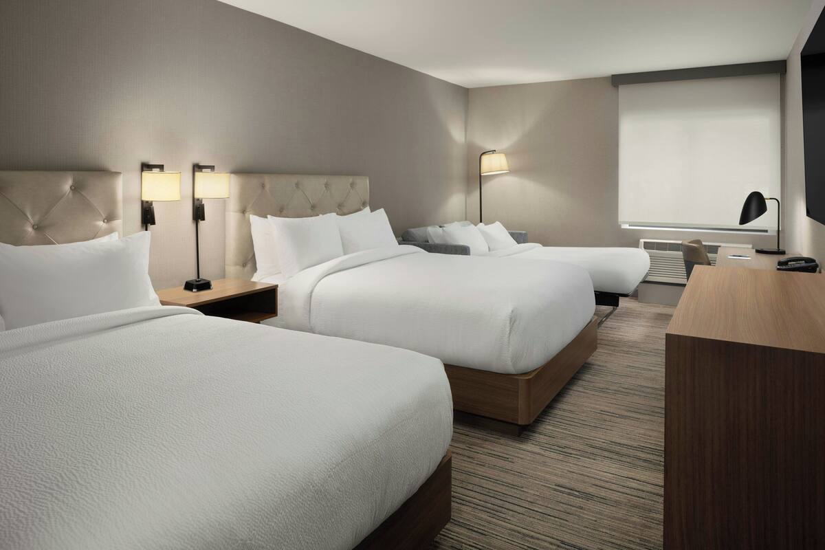 Una habitación de hotel con dos camas, un escritorio, una silla y un televisor.