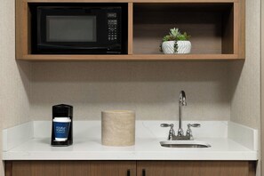 A kitchen with a microwave, a coffee machine, a sink, and a small potted plant. - Four Points by Sheraton Downtown Seattle Center (Seattle)