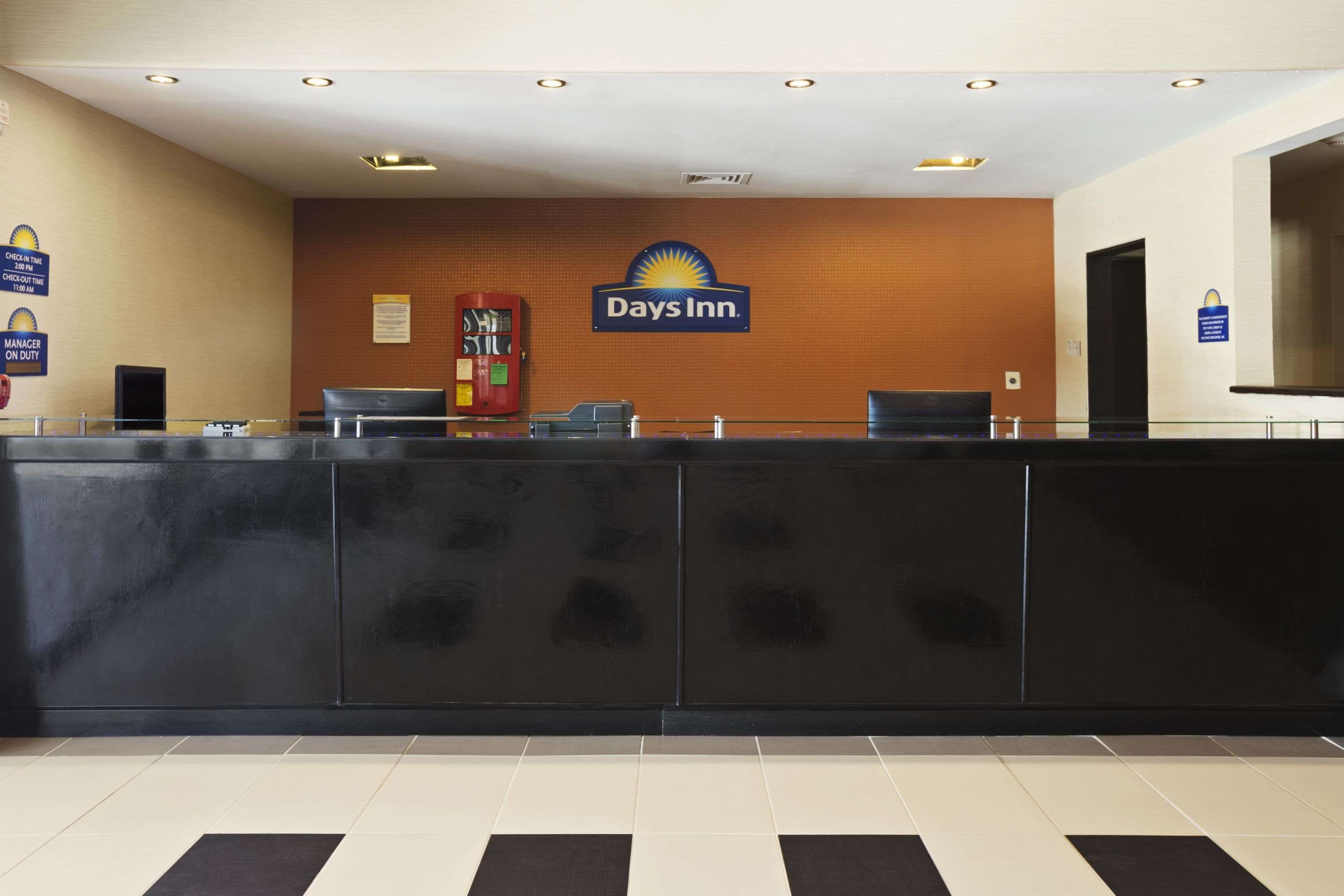 Un mostrador de recepción con el logotipo de Days Inn, un teléfono rojo y una computadora.