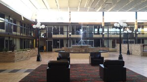 Eine geräumige Lobby mit einer zentralen Springbrunnen, mehreren Sitzbereichen und einer hohen Decke mit Tageslicht.