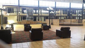 A spacious lobby with a fountain, multiple seating areas, and a large glass wall providing a view of the building's interior.