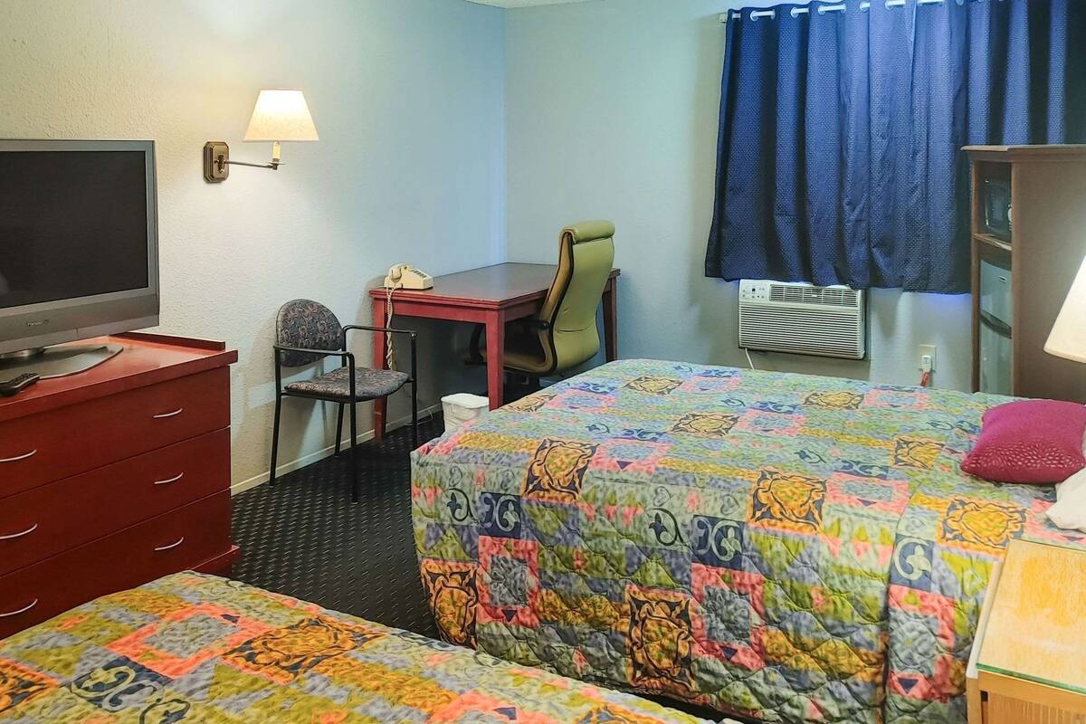 Ein Hotelzimmer mit Bett, Schreibtisch, Stuhl, Fernseher und Kleiderschrank.