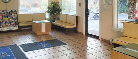 A reception area with a clock, a bulletin board, a plant, and seating.