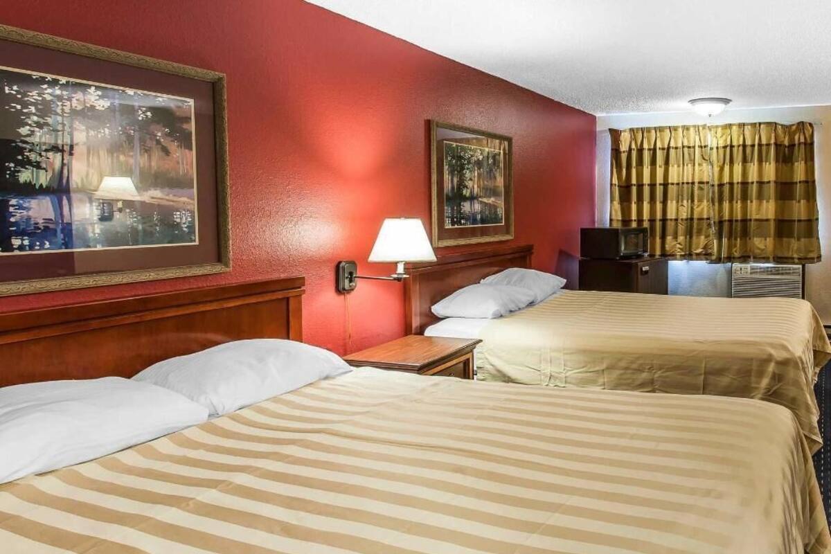 Ein Hotelzimmer mit zwei Betten, einem Nachttisch, einer Lampe und einem Bild an der Wand.
