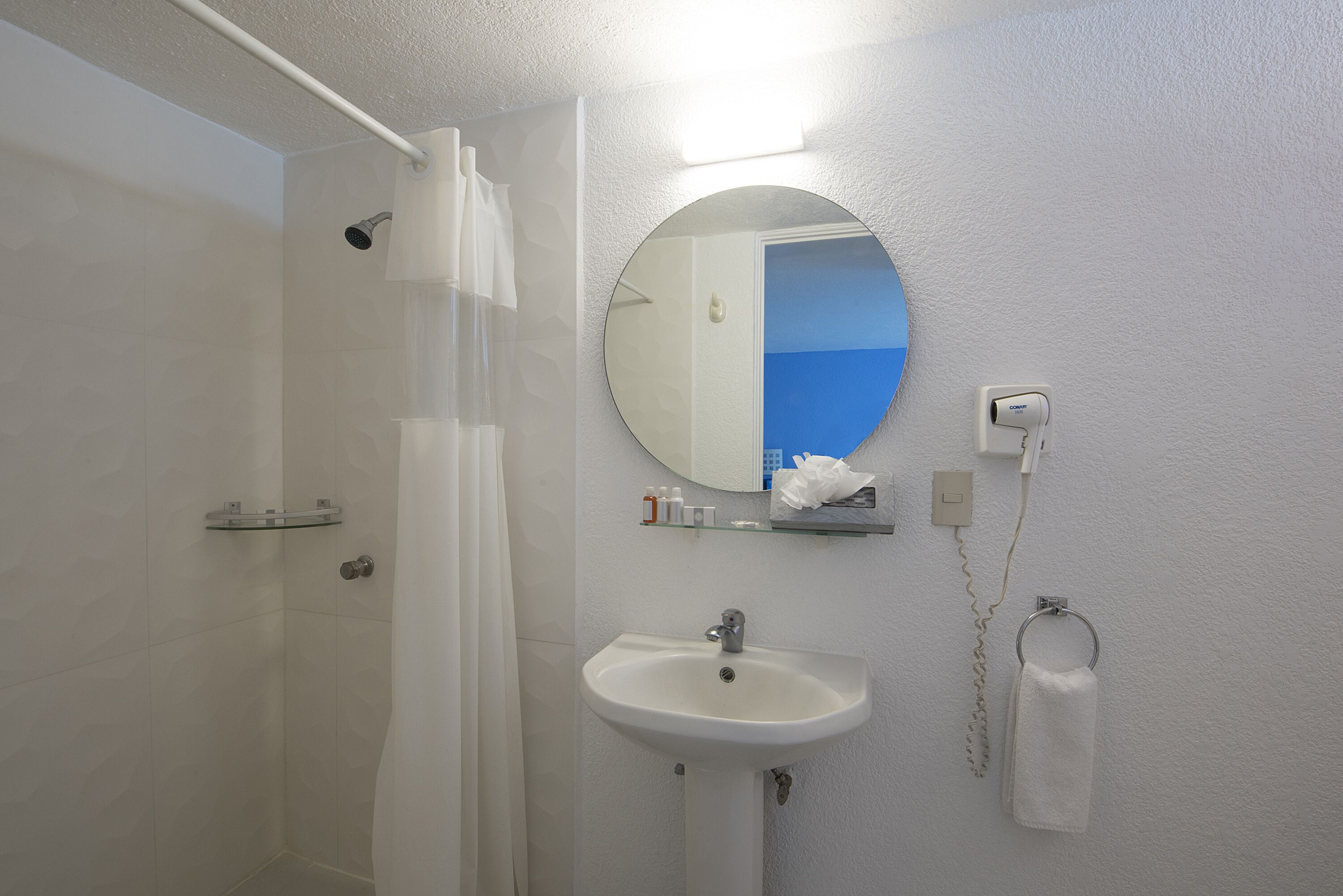 A bathroom with a shower, sink, and mirror.