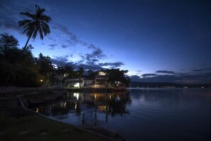 A waterfront property with a dock, a palm tree, and a building reflecting on the water.