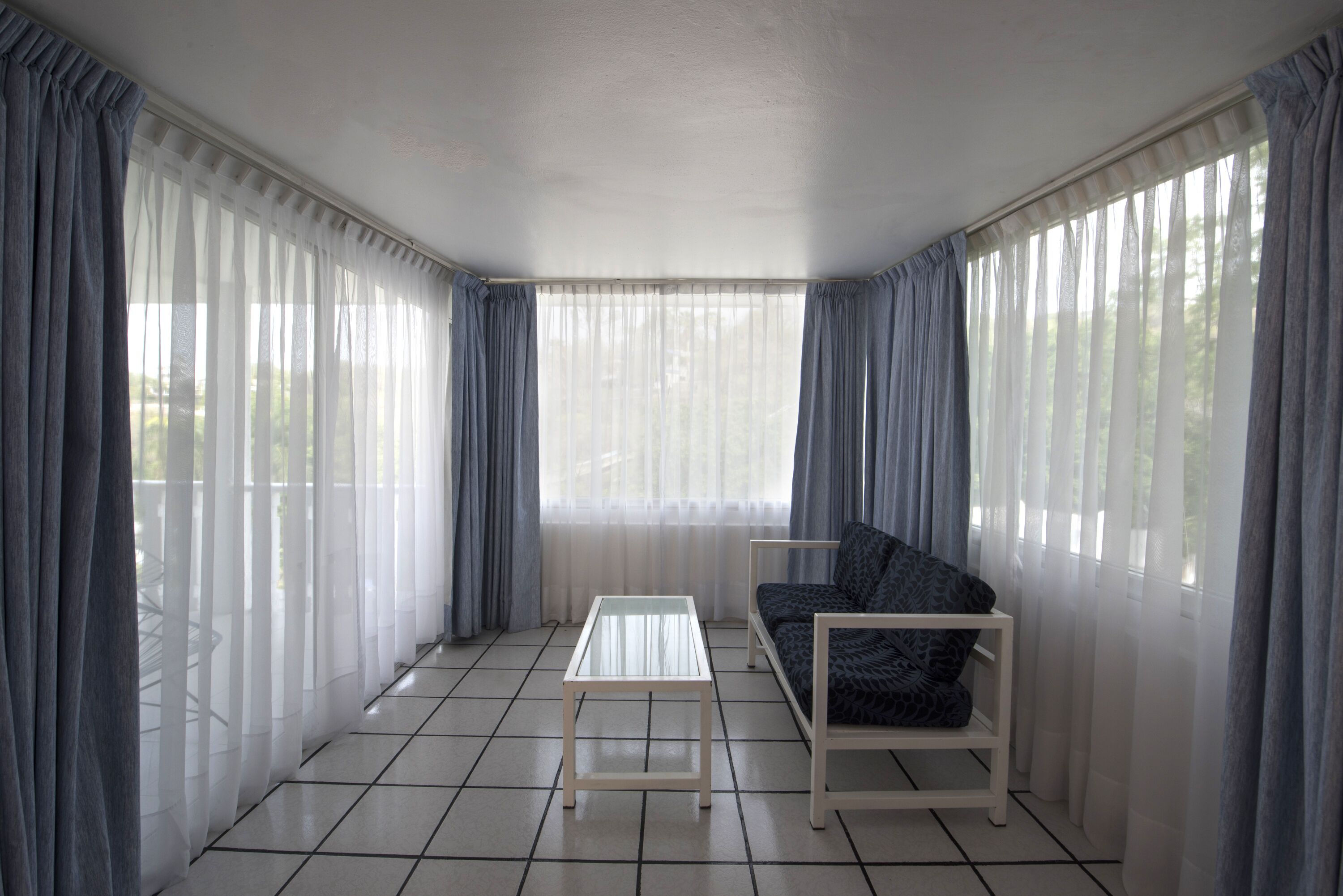 A room with a sofa, a small table, and sheer curtains.