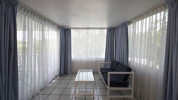 Una habitación con sofá, una mesita y cortinas ligeras.