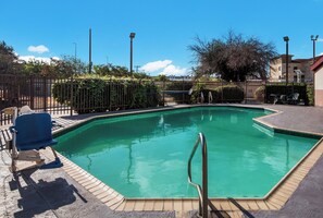 A rectangular swimming pool with a tiled edge, a metal ladder, and a few lounge chairs. - Red Roof Inn San Antonio - Seaworld/ Northwest (San Antonio)