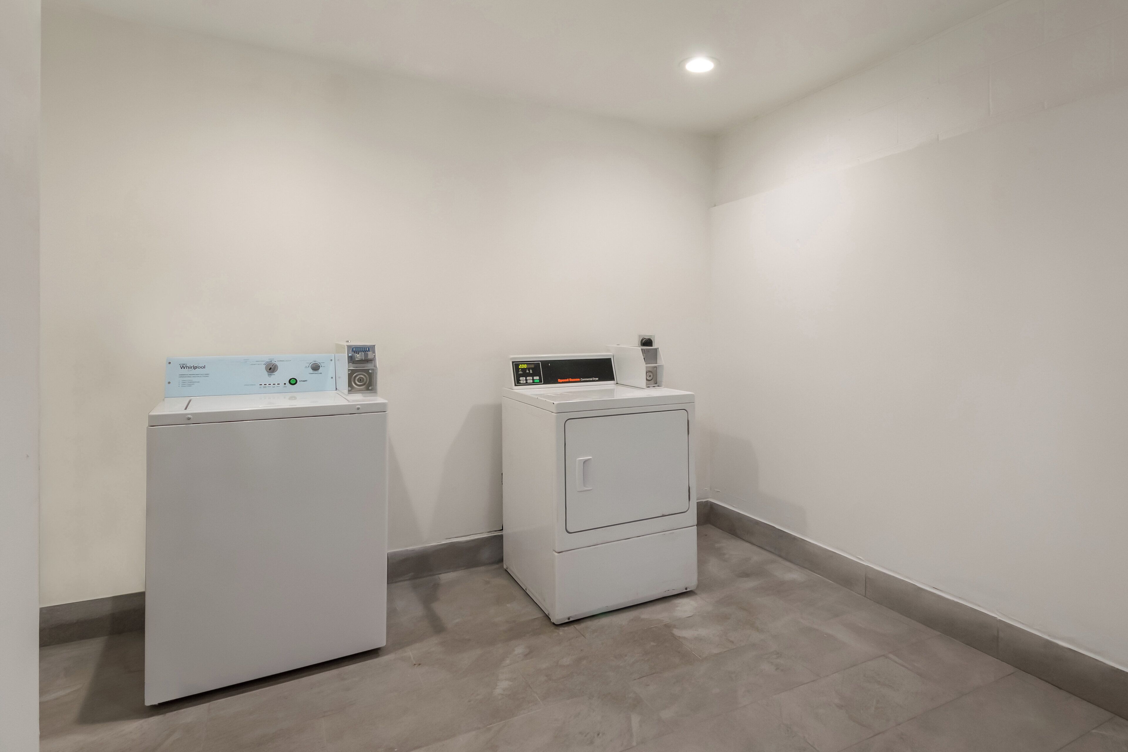 A laundry room with two white appliances, one with a control panel and the other with a digital display.