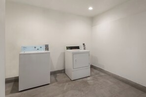 A laundry room with two white appliances, one with a control panel and the other with a digital display.